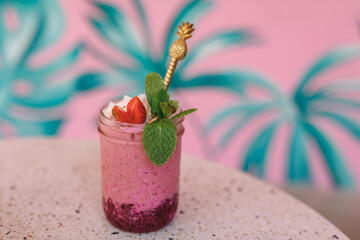 Strawberry smoothie or milkshake in mason jar on pink pastel background. Healthy food for breakfast and snack