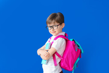 Cute little schoolboy on color background