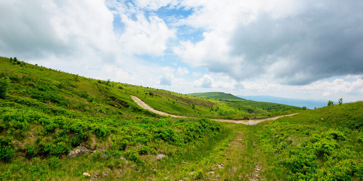 path through mountain landscape. road through green rolling hills. cloudy weather