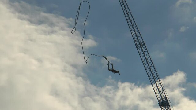 Man jumping from a tower for bungee jumping and coming down, and then 
up at the beautiful sky with clouds.