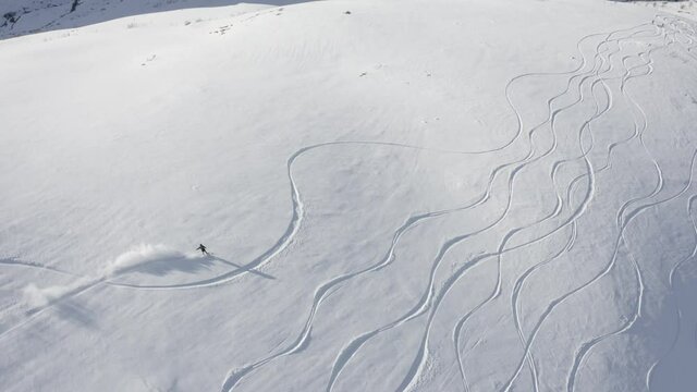 Aerial footage of a snowboarder riding down a mountain.