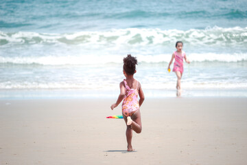 Little cute kid girl  having fun on sandy summer with blue sea, happy childhood friend running and  playing on tropical beach