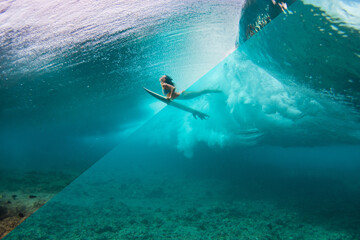 Example of editing underwater photography. more contrast and colourful compare raw file. Young woman in the bikini doing surfing and  duck dive at the point break under the wave.
