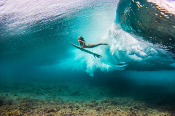 Fototapeta woman in bikini doing duck dive with the surfboard under the waves obraz