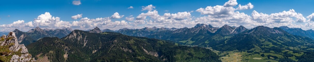 Fototapeta na wymiar Panorama Tannheimer Berge vom Sorgschrofen bis zum Kühgundkopf bei blauem Himmel und leichten Quellwolken