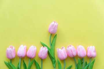 Yellow and pink tulips placed on a wooden table.