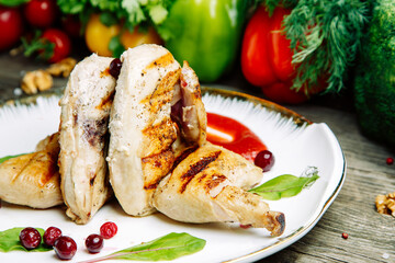 Restaurant dish with vegetable decor on a wooden background. Tobacco chicken with sauce and herbs on a plate.