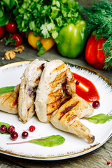 Restaurant dish with vegetable decor on a wooden background. Tobacco chicken with sauce and herbs on a plate.