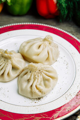 Restaurant dish of Georgian cuisine. Hot khinkali on a plate with pepper.
