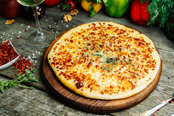  Azerbaijani restaurant dish with vegetable decor on a wooden background. Khachapuri in Megrelian on the Board.