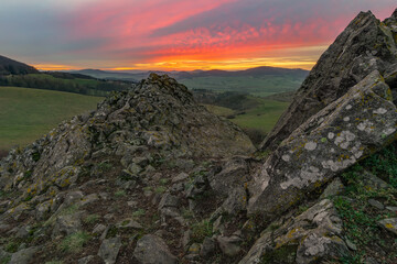 Red and orange sunset in cloudy blue sky over the green and atmospheric mountains of Kassel in Germany