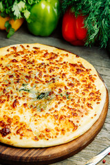  Azerbaijani restaurant dish with vegetable decor on a wooden background. Khachapuri in Megrelian on the Board.