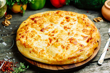  Azerbaijani restaurant dish with vegetable decor on a wooden background. Khachapuri in Megrelian on the Board.