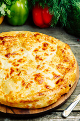  Azerbaijani restaurant dish with vegetable decor on a wooden background. Khachapuri in Megrelian on the Board.