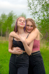 Two teenage girls with long hair on a walk hug each other. The concept of friendship, same-sex relationships. 