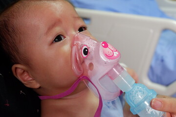 Sick boy inhalation therapy by the mask of inhaler. Boy is sick with Respiratory Syncytial Virus. Patient Boy use inhalation with Nebulizer mask at hospital. The baby are spraying bronchodilators .
