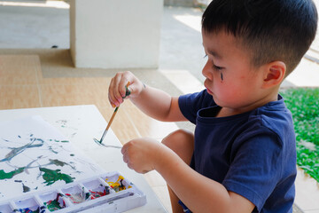 Beautiful little boy having fun painting with water colors
