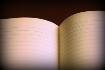 Open notebook with lined pages on a dark background. Retro style toned, vignetting