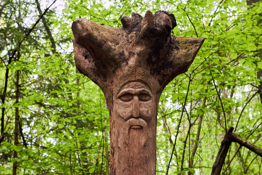 The image of the Slavic deity Veles carved from root of a tree on a neo-Pagan temple in the forest. Kaluzhskiy region, Russia. Veles - the god of cattle breeding, wealth and wisdom