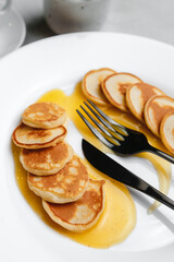 Trendy homemade Breakfast with mini pancakes and orange sauce on a white table. The view from the top. Side view. Space for text