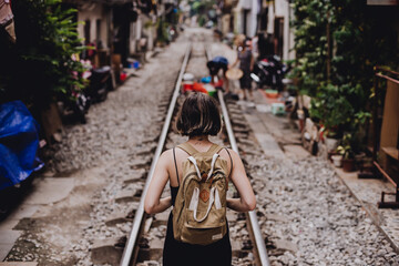 young woman with a backpack on a street with train tracks in Hanoi, Vietnam
