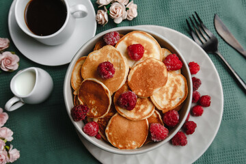 Trendy homemade Breakfast mini pancakes with raspberries and coffee on a white table. The view from the top. Side view. Space for text