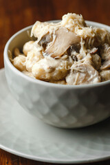 Potato gnocchi, Italian potato dumplings with cheese sauce, mushrooms and herbs on a plate. Side view, top view
