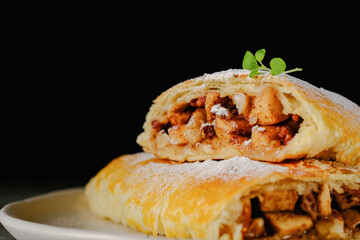 Apple strudel cut on a black background background blurred