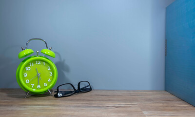 alarm clock with spectacle on a wooden table