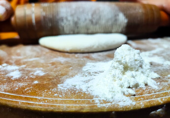 Baking flour with rolled dough and rolling pin on wooden board. Pizza cooking background.