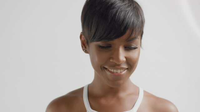 Mixed race black woman with soft healthy skin in studio watching to the camera and smiling. High quality 4k footage