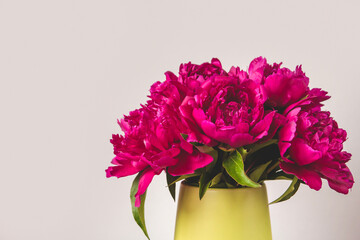 A bouquet of bright pink peonies in a green vase copy space. Blooming peonies. A bouquet of peonies as a gift.