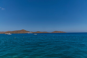 Summer sea view from coast with white yaht and mountains in background, Greece