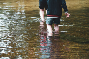 Children playing outside in a shallow stream paddling in the water