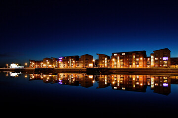 Fototapeta na wymiar Quayside Apartment Building at night with reflections in the water. 