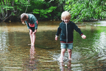 Children paddle in a stream of water outside during a sunny day out together