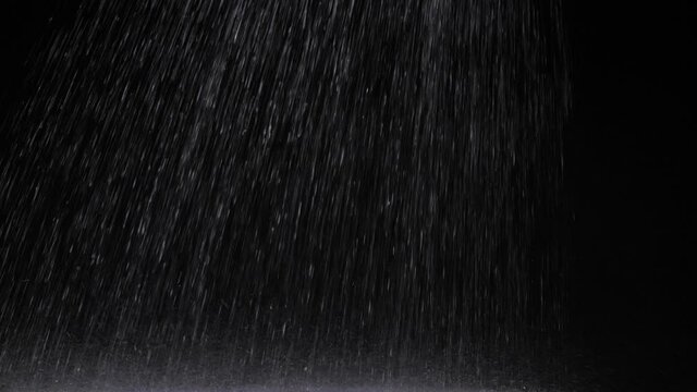 studio rain shower rain against black background on glass plate

