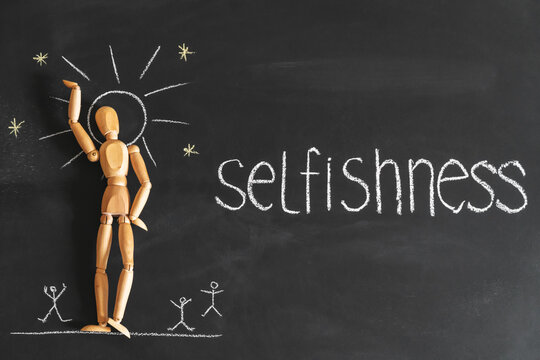 Concept of narcissism and selfishness. Wooden man on the background of chalk board.