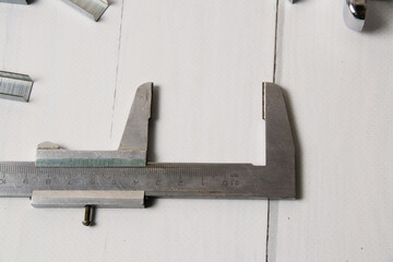 Construction ruler and metal staples for a stapler on a light wooden background with copy space. The concept of construction, repair, improvement of housing conditions