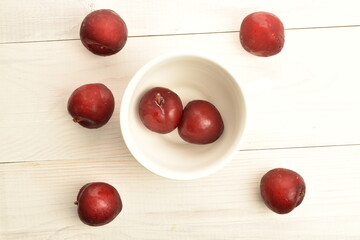 Juicy, tasty, organic red plum, close-up, on a painted wooden table.