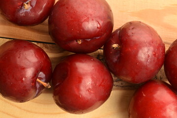 Juicy, tasty, organic red plum, close-up, on a wooden table.