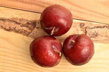 Juicy, tasty, organic red plum, close-up, on a wooden table.