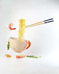 Yellow seafood prawn coriander leaf noodle soup elevated flying suspended in air with soup spoon and chopstick prawn coriander leaf tofu on white background