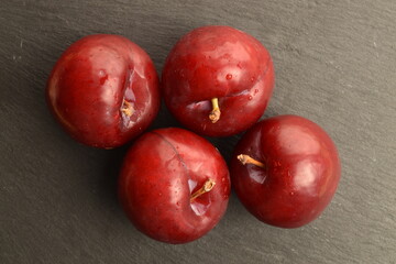 Juicy, tasty, organic red plum, close-up, on a serving plate of slate.