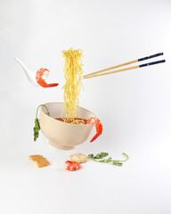 Yellow seafood prawn coriander leaf noodle soup elevated flying suspended in air with soup spoon and chopstick prawn coriander leaf tofu on white background