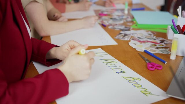 Hands of woman sitting at table and drawing vision board with her wishes and goals in group female therapy session