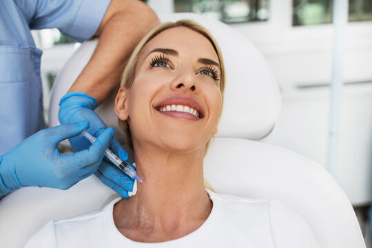 Attractive blond woman is getting a rejuvenating facial injections at beauty clinic. The expert beautician is filling female wrinkles by botulinum.