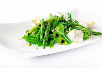 Warm salad made of green peas pods, string beans, asparagus, lettuce leaves, brie cheese, cedar nuts and olive oil.