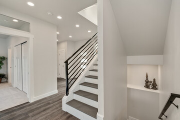 Modern iron staircase in a spacious foyer designed with grey hardwood floor.