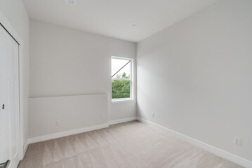 Empty room with a window, white painted walls, carpet floor and built-in closet